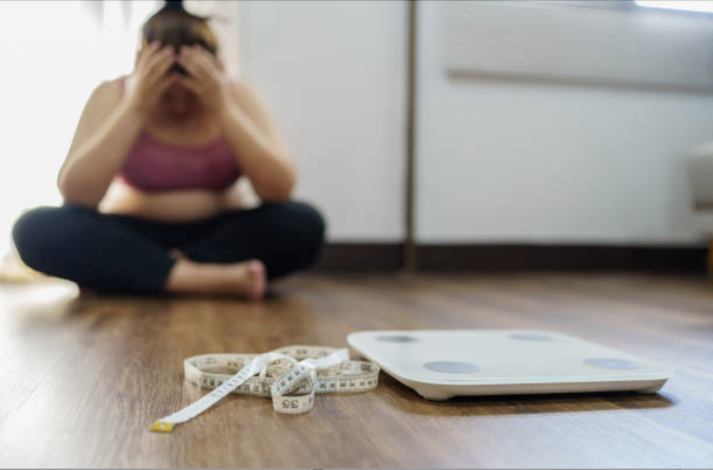 Person on a scale reflecting on a weight loss plateau on GLP-1 medication
