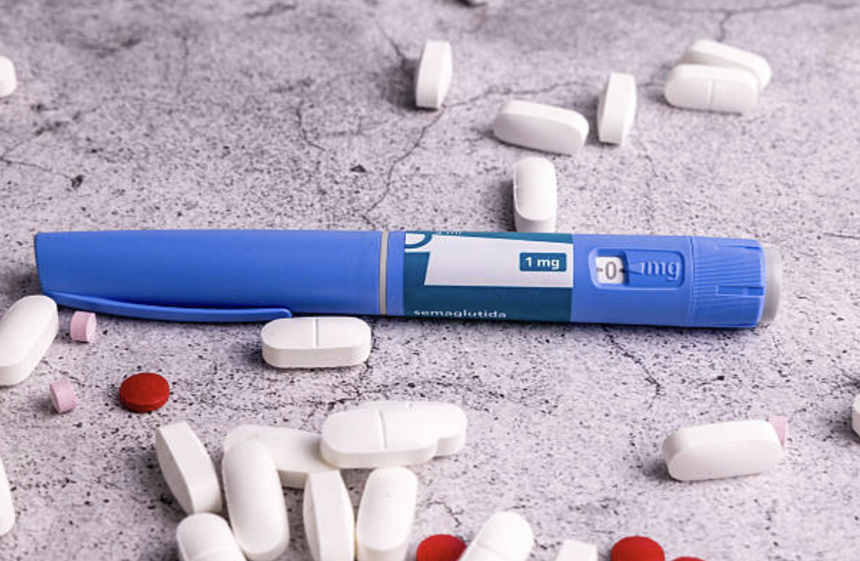 Person holding oral weight loss pill next to injectable pen comparing GLP-1 medication options