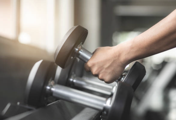 Person grabbing dumbbells at gym for resistance training during GLP-1 treatment